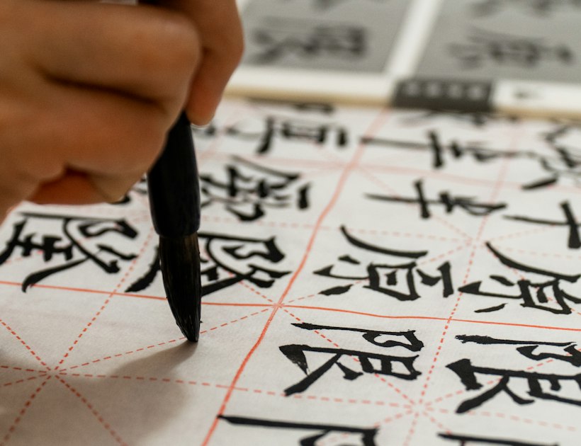 Mano escribiendo caligrafía china con pincel y tinta